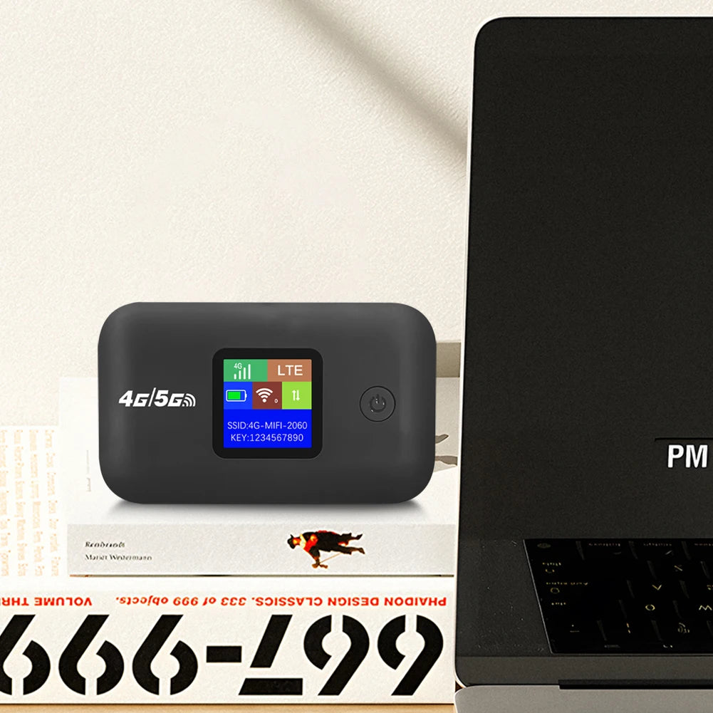 Compact black portable 4G LTE Wi-Fi hotspot with a clear digital status screen, sitting on a book next to a laptop.