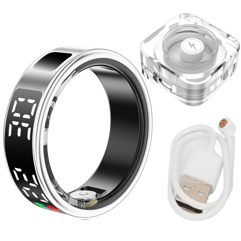 Silver and black smart fitness ring with digital display, magnetic charging dock, and white USB charging cable.