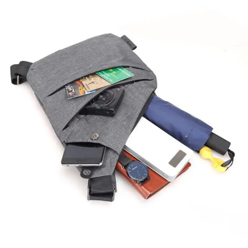 Grey slim crossbody chest bag with zipped compartments, holding a smartphone, power bank, wallet, watch and umbrella.