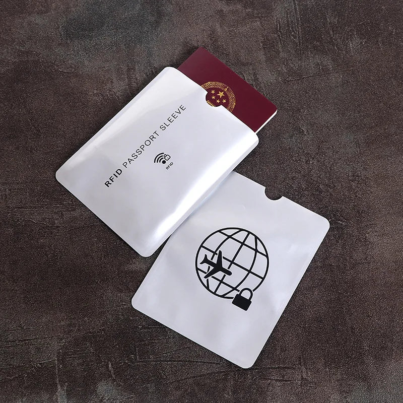 Two white plastic RFID-blocking passport sleeves, one containing a red passport, on a dark textured background.