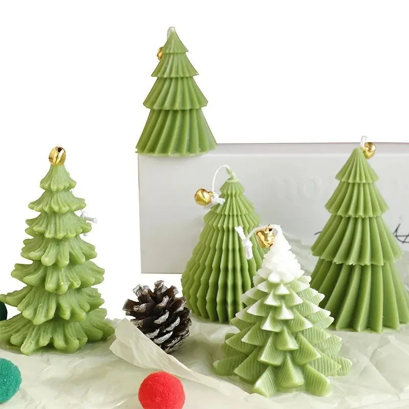 Set of green Christmas tree-shaped candles with small gold bell toppers and textured needle detail.