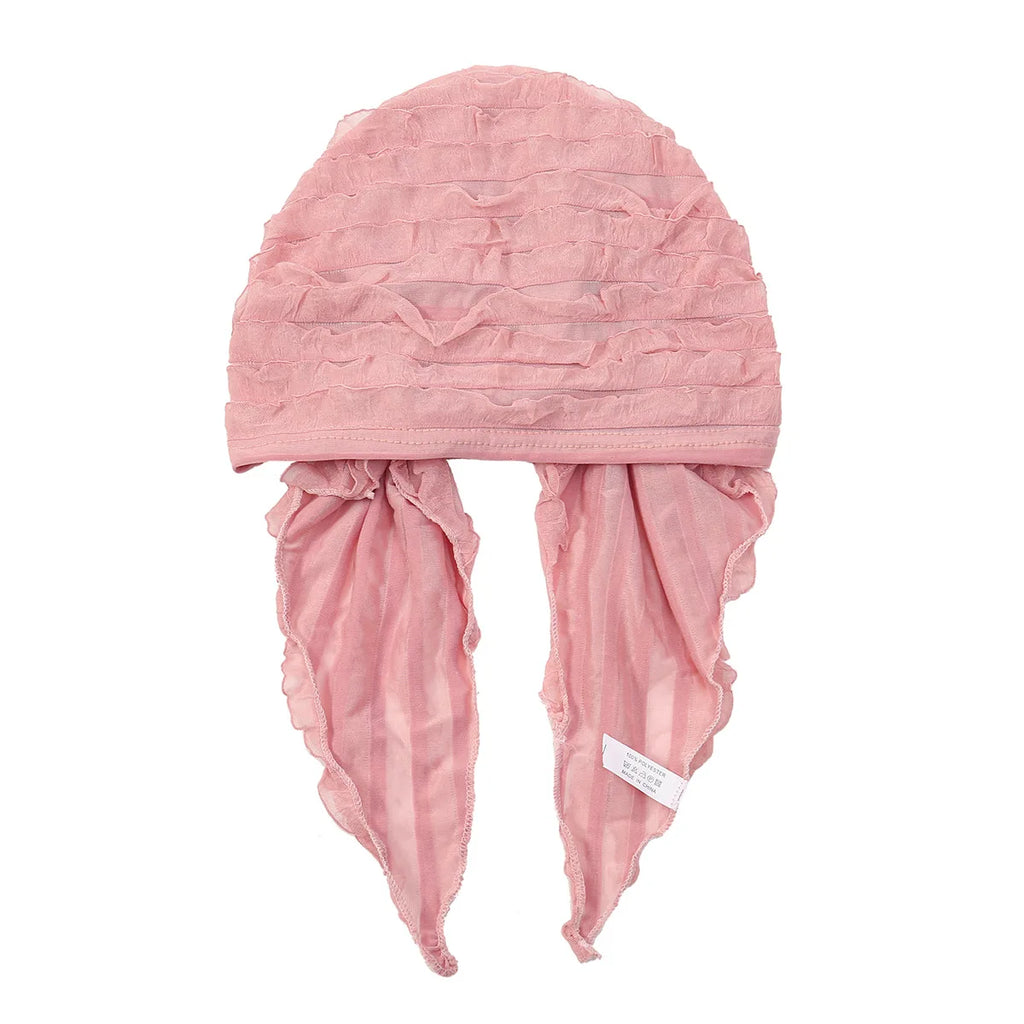 Dusty pink pre-tied elastic turban head wrap with textured ruffle detailing and two soft hanging side ties.