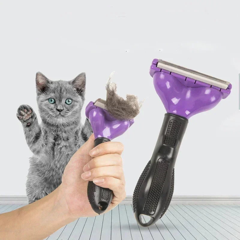 Purple pet de-shedding tool with a black grip handle, shown held by a hand next to a grey kitten.
