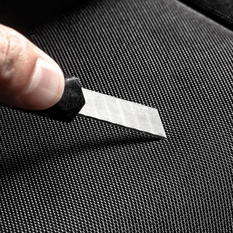 Close-up of a sharp blade pressing against durable, black anti-theft fabric, demonstrating cut-resistant material.
