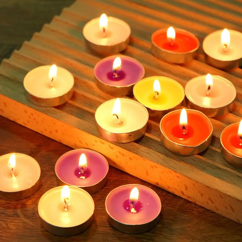 Assorted lit multi-coloured tea light candles in metal cups arranged on a grooved wooden stand.