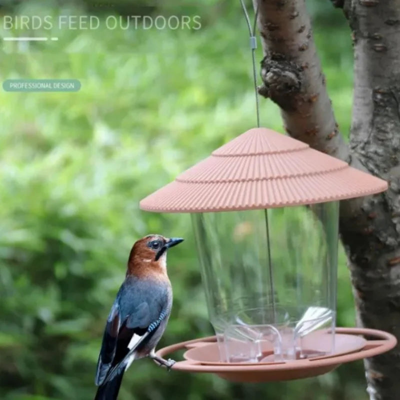 Clear plastic bird feeder with a ridged, peach-colored cone roof and base, hanging from a tree branch.