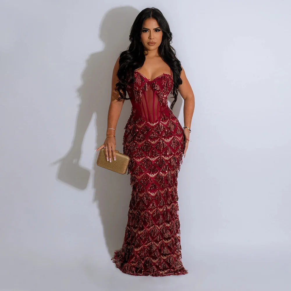 Burgundy sequin maxi dress featuring spaghetti straps, a sheer corset bodice, and floor-length fit.
