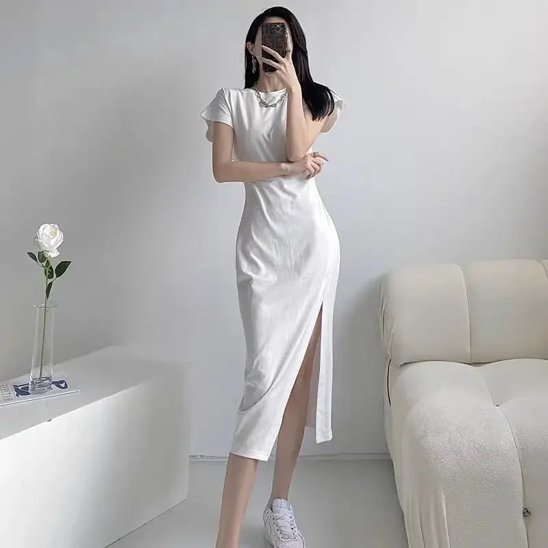 A model wears a white midi dress with short flutter sleeves, a round neckline, and a side leg slit.