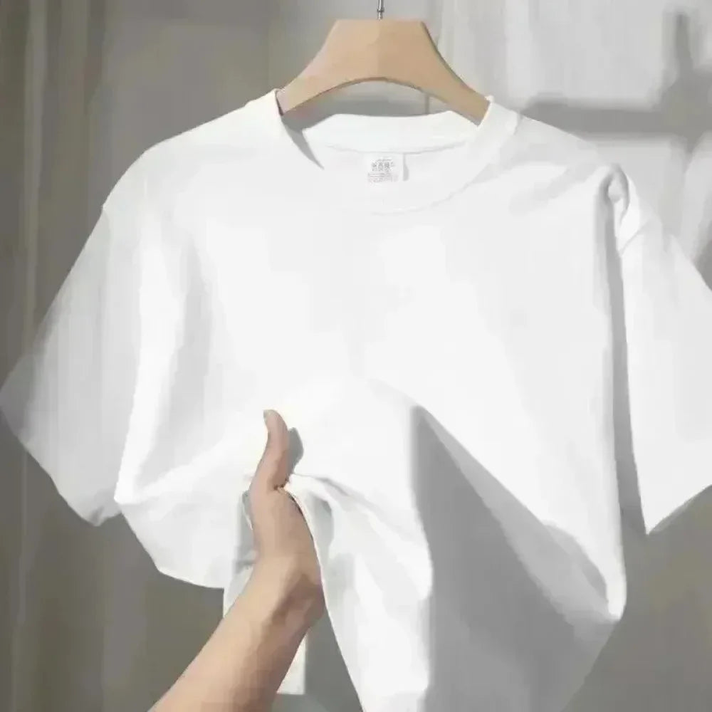 Classic white crew neck t-shirt with short sleeves, held on a wooden hanger, soft cotton fabric texture.