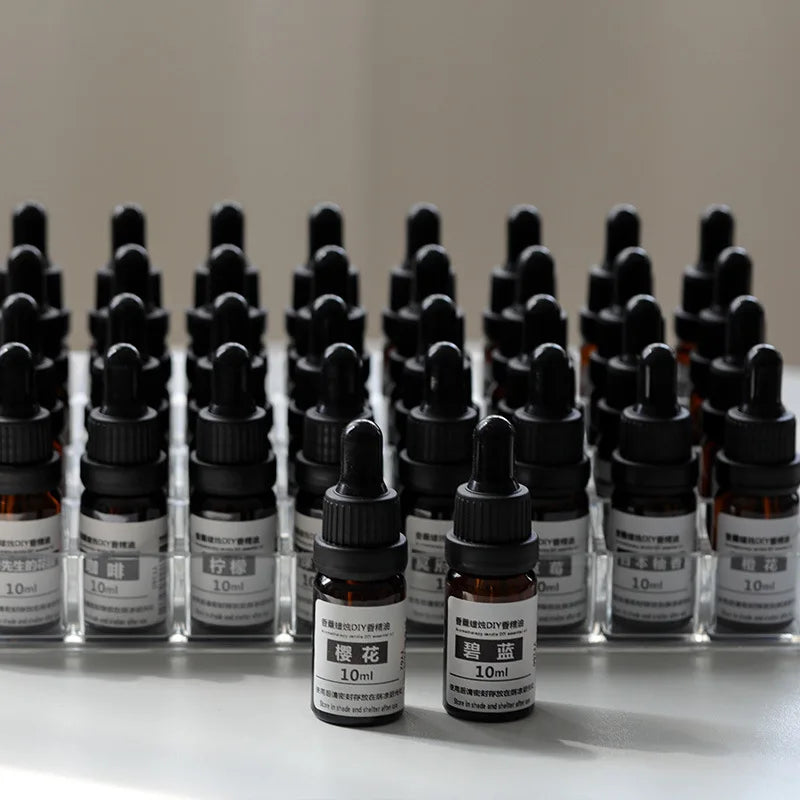 Rows of 10ml amber glass essential oil dropper bottles with black caps, neatly arranged in a clear plastic display tray.