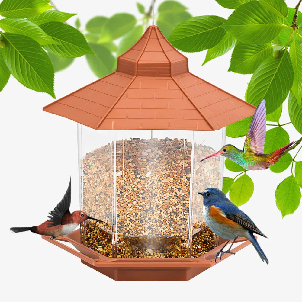 Hexagonal brown bird feeder with a pagoda-style roof, clear seed reservoir, and birds feeding on green foliage background.