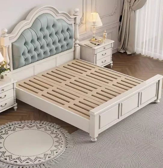 Elegant white wooden double bed frame with a button-tufted sage green upholstered headboard and slatted base.