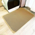 Tan, heavy-duty waterproof cat litter mat with a honeycomb mesh design, placed on a wooden floor by a litter box.