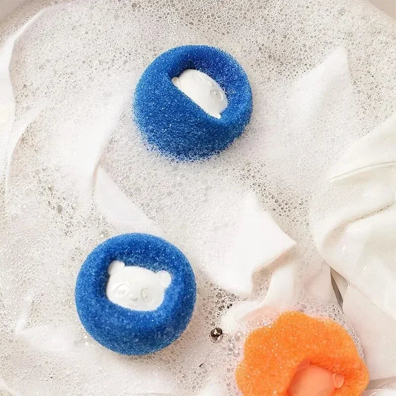 Two blue circular scrubbing sponges, each with a white bear-shaped centre, floating in soapy water.