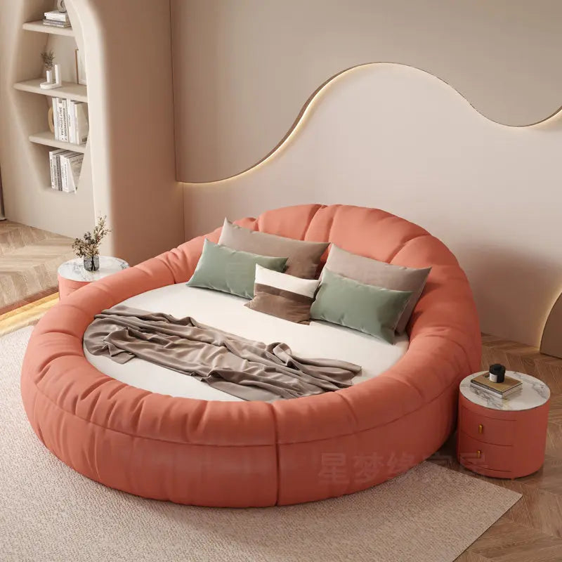 A modern, round coral-pink upholstered bed frame with a minimalist, tufted design in a bedroom setting.
