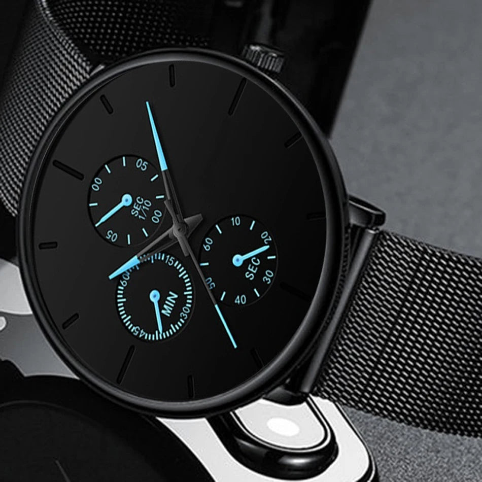 Ultra-thin men’s black stainless steel quartz watch with a mesh strap and luminous blue hands on a matte black dial.