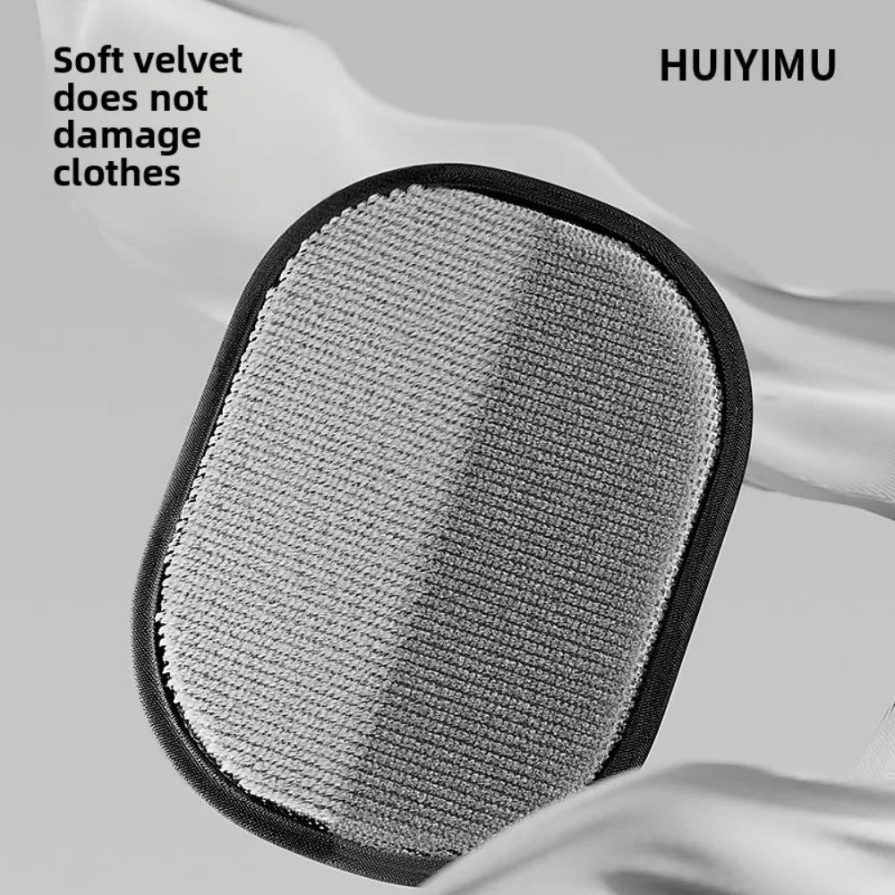 An oval grey velvet lint remover pad with a black fabric border, set against a soft grey background.