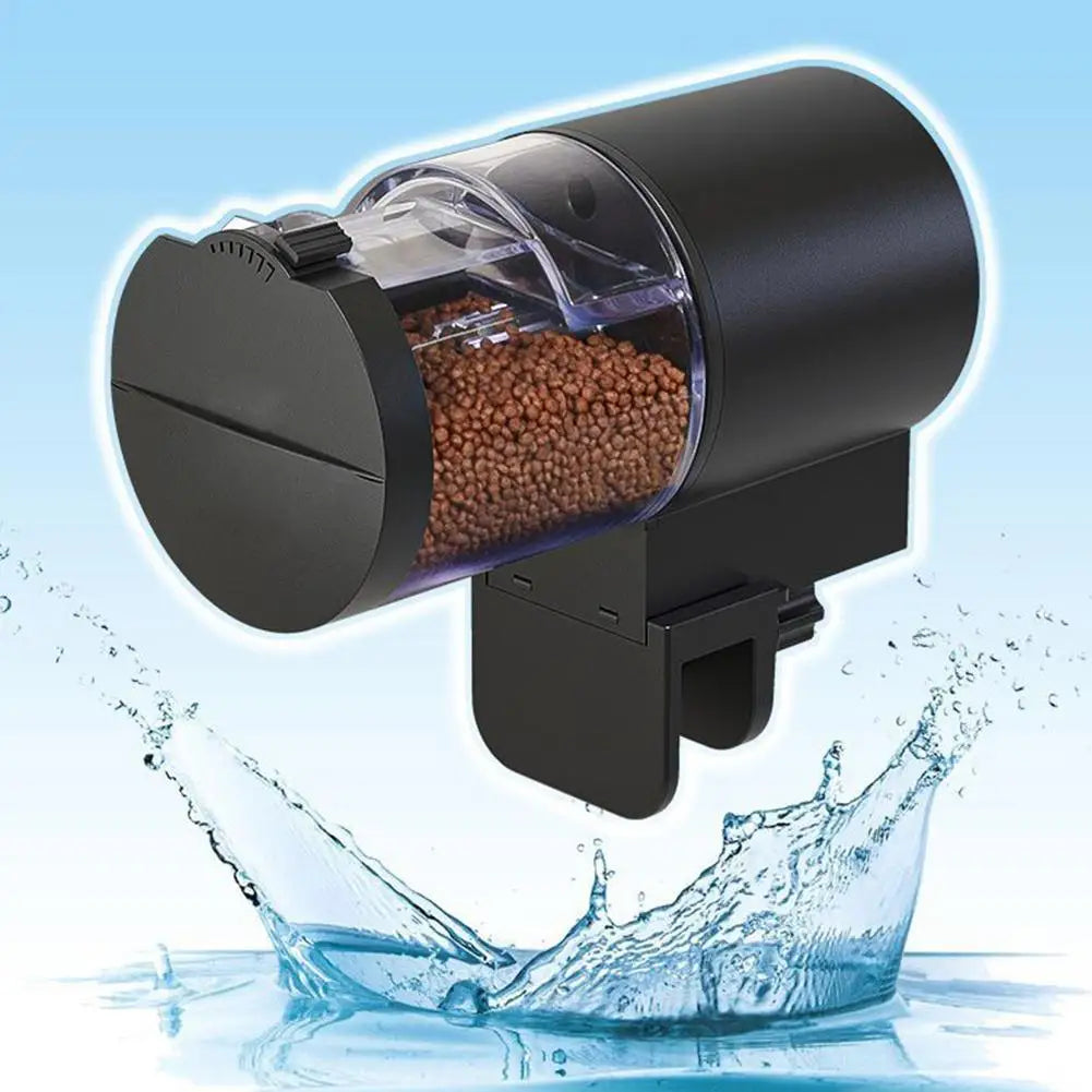 Black automatic fish feeder with a clear, barrel-style food container filled with brown pellets, over a water splash.