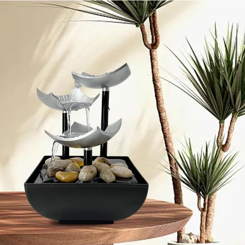 Modern three-tier silver lotus-style tabletop water fountain with smooth decorative river stones in a black base.
