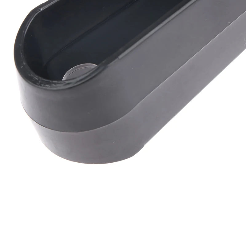 Close-up of a matte black, oval-shaped plastic mounting bracket with a pre-drilled screw hole.