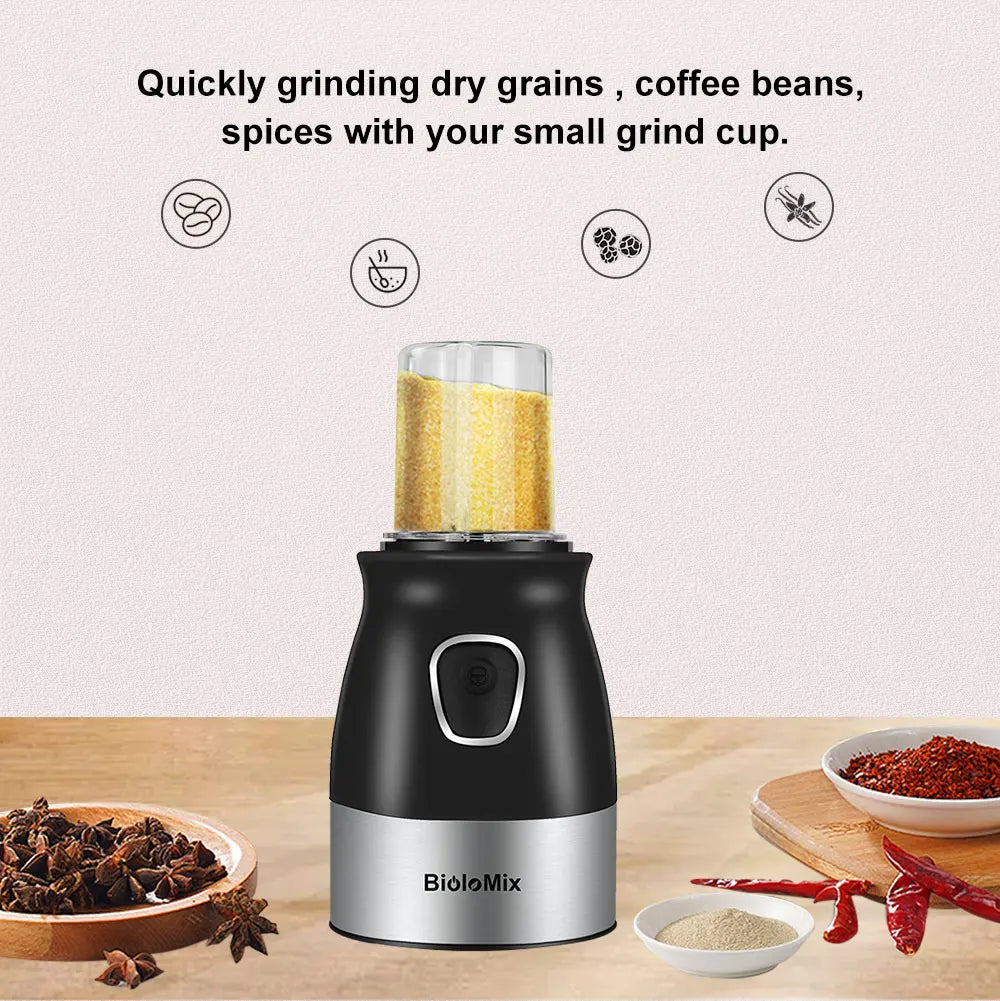 Black and silver electric grain and spice grinder with a transparent cup filled with ground grains on a wooden table.