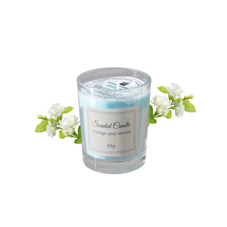 Blue scented candle in a small glass jar, labelled "Scented Candle", accented with sprigs of white jasmine flowers.