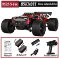 Black and red RC monster truck with massive treaded tires, front LED lights, rear wing, batteries, and controller.