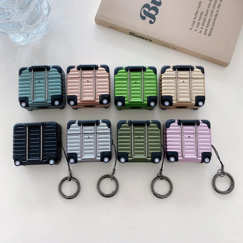 Hard-shell, suitcase-style AirPods cases in various metallic colours, featuring a luggage handle and keychain ring.