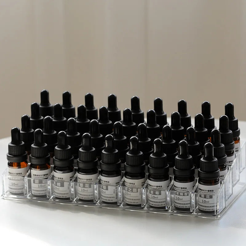 Clear acrylic tiered stand holding 40 amber glass essential oil bottles with black dropper caps.