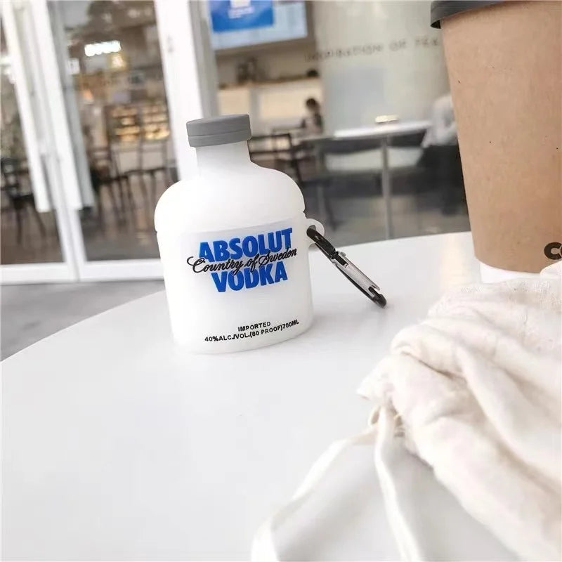 White silicone AirPods case shaped like an Absolut Vodka bottle with a grey cap and black carabiner attachment.
