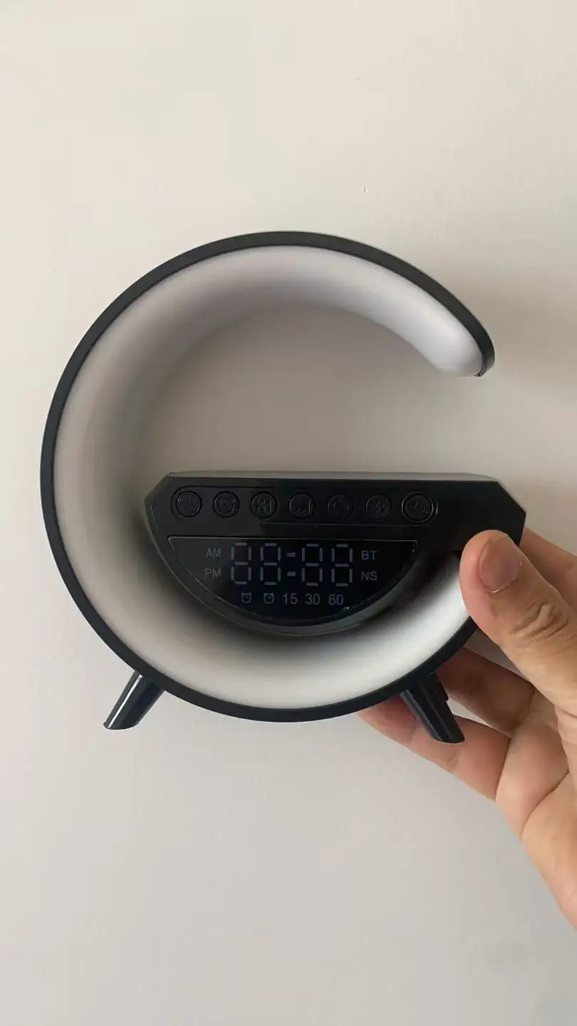 Black and white C-shaped LED alarm clock with digital display, Bluetooth connectivity and wireless charging base.