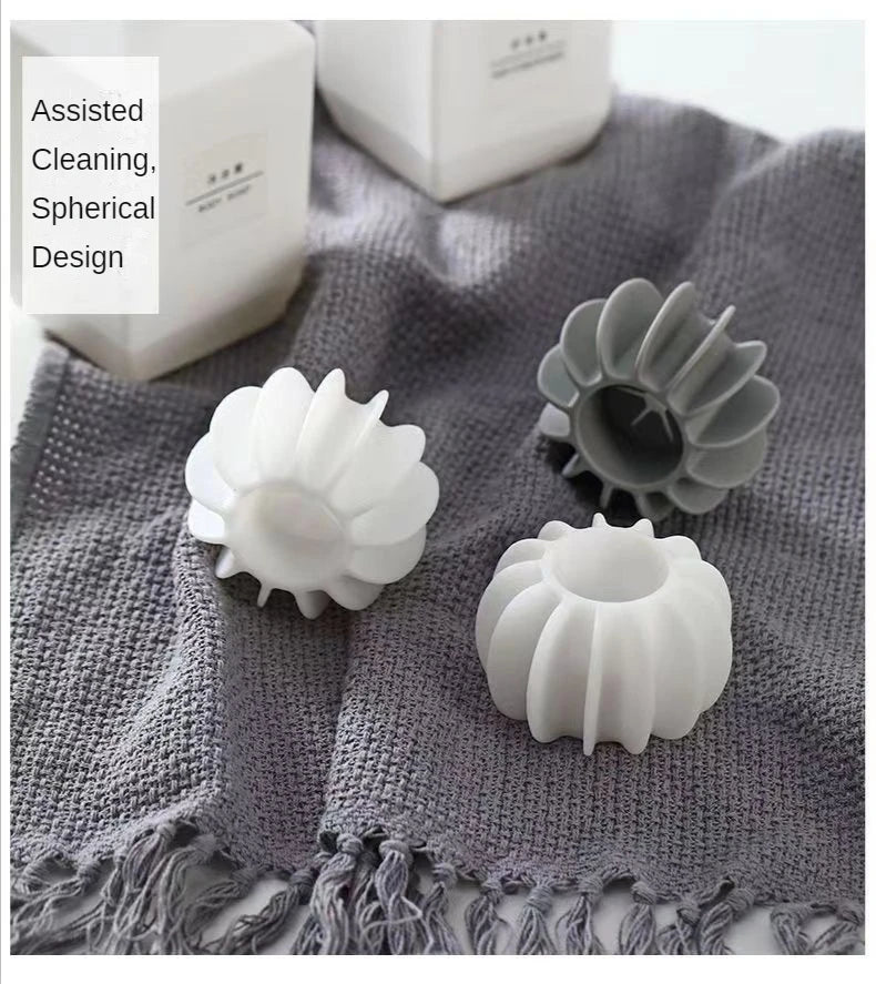 Three white and grey spherical, ribbed cleaning tools sitting on a grey textured fabric cloth.