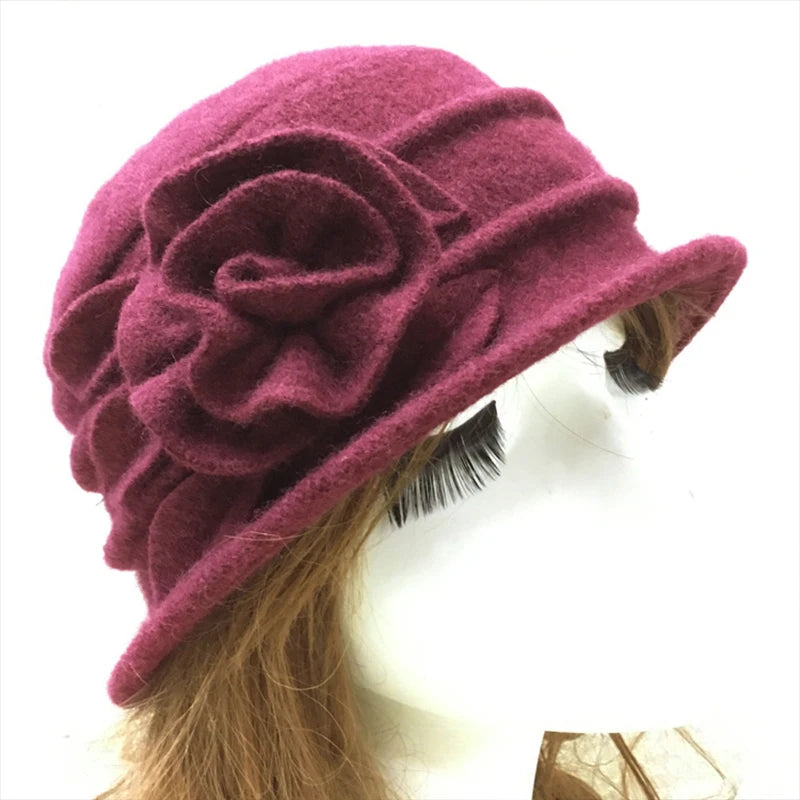 A plum-coloured wool winter hat with an elegant felt flower detail and a small turned-up brim.