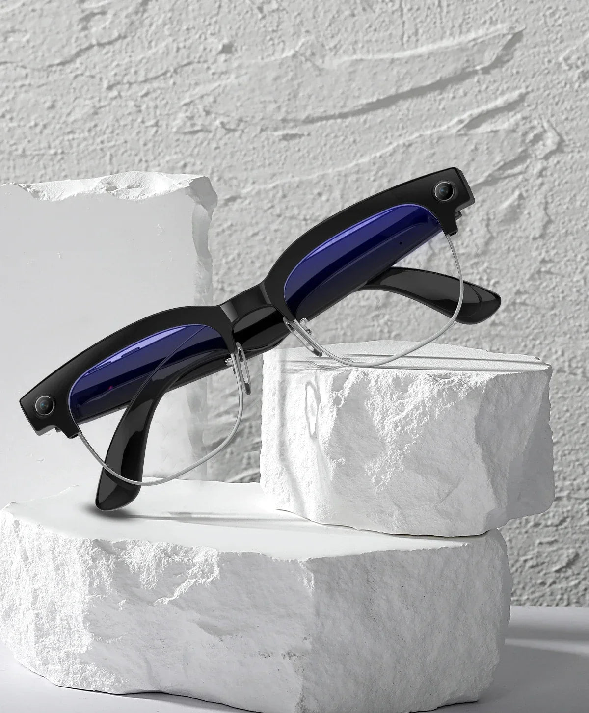 Black smart glasses with integrated cameras and blue-tinted lenses, resting on textured white stone blocks.