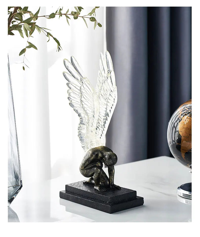 Bronze-effect kneeling figure ornament with translucent, detailed angel wings on a black rectangular base.