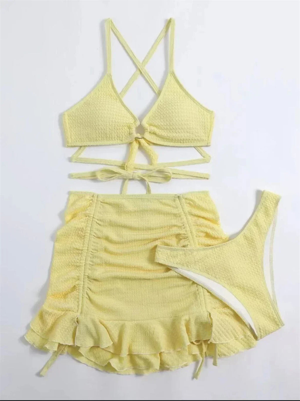 Yellow three-piece swimsuit with ring-linked halter top, criss-cross ties, bottoms, and ruffled skirt.