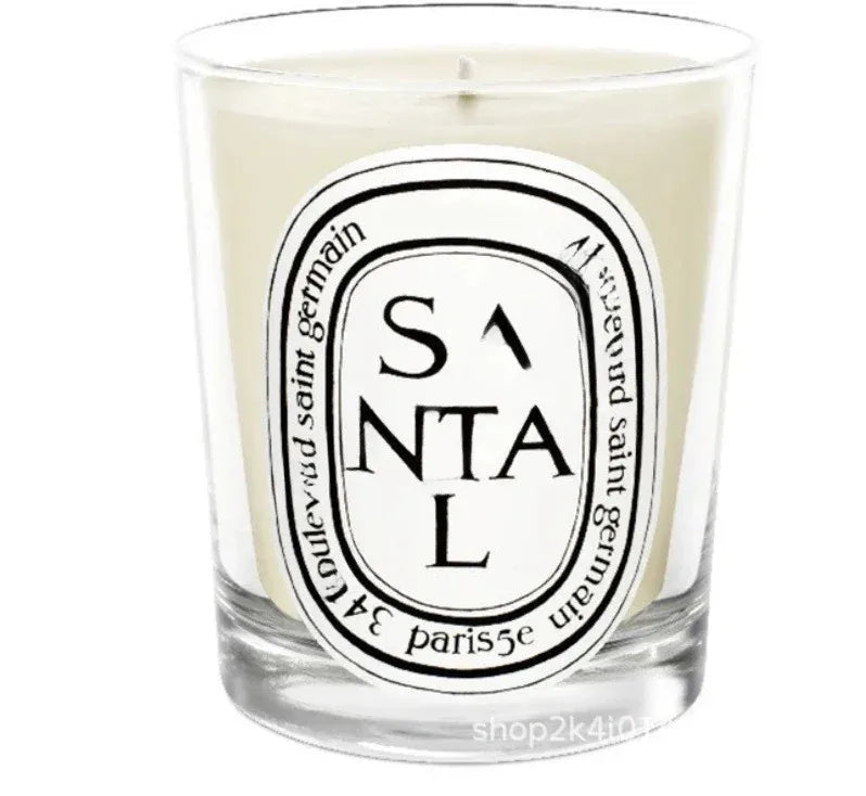 Scented candle in a clear glass jar with a white oval label featuring black decorative text reading SANTAL.