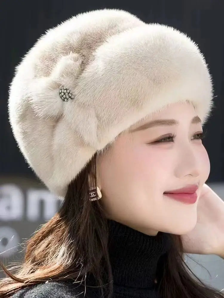 A woman wearing an elegant, cream-coloured faux fur winter hat featuring a decorative, crystal-embellished side detail.