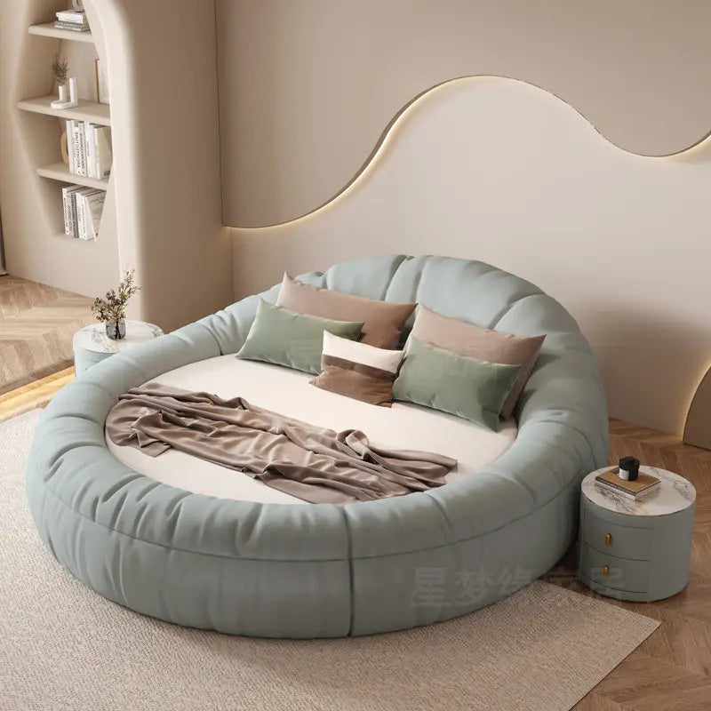Modern sage green round bed frame with a soft, padded upholstered finish, featuring decorative scatter cushions.