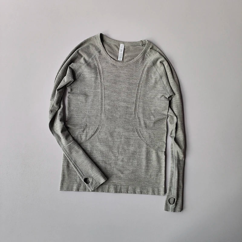 Grey seamless long-sleeve athletic top with ribbed cuffs, thumbholes, and decorative contour paneling.