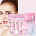 Full skincare set in pink packaging, featuring mud masks, cleanser, creams, serum, lip mask, headband, and brush.