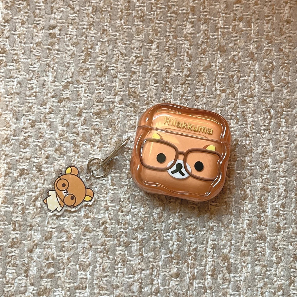 Brown Rilakkuma clear silicone AirPods case with matching charm, featuring bear character with glasses.