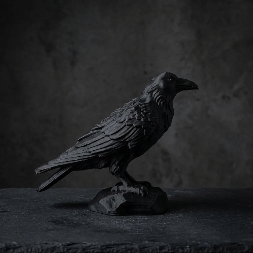 Matte black raven bird ornament perched on a textured rock base, featuring detailed feather sculpting.