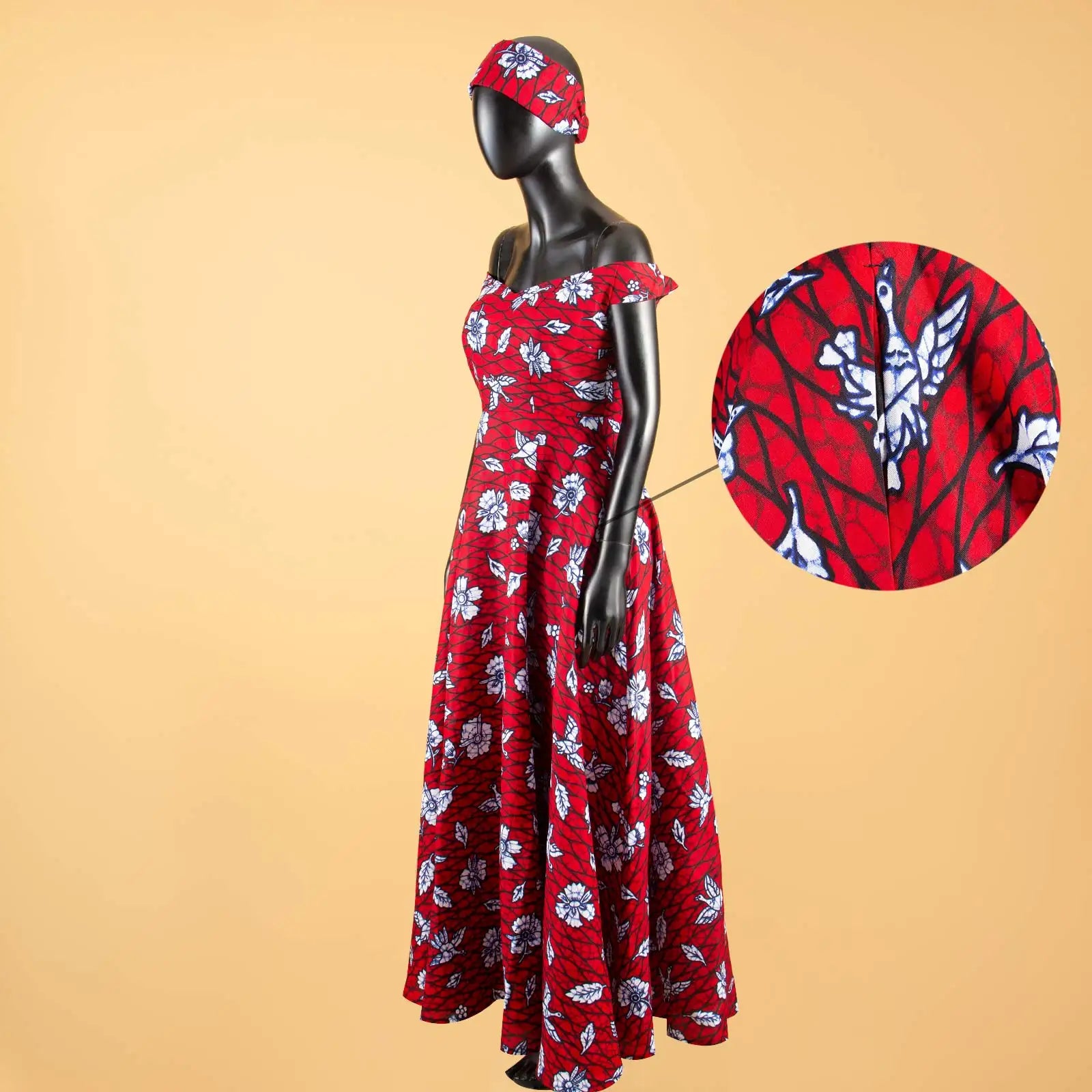 Red off-shoulder maxi dress with a white floral and bird print, featuring a matching headband on a mannequin.
