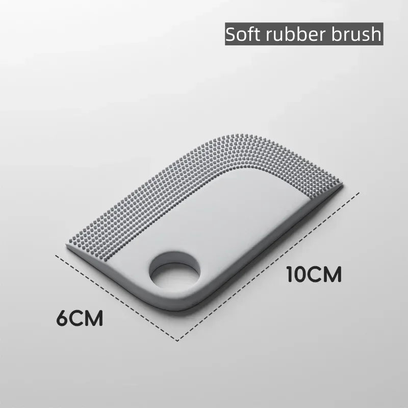 Grey soft rubber brush with a textured edge and finger hole. Size is 10cm by 6cm.