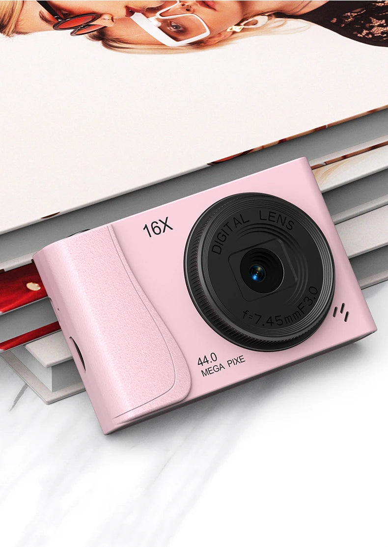 Pink digital camera with a black lens, featuring 16x zoom and 44-megapixel resolution.