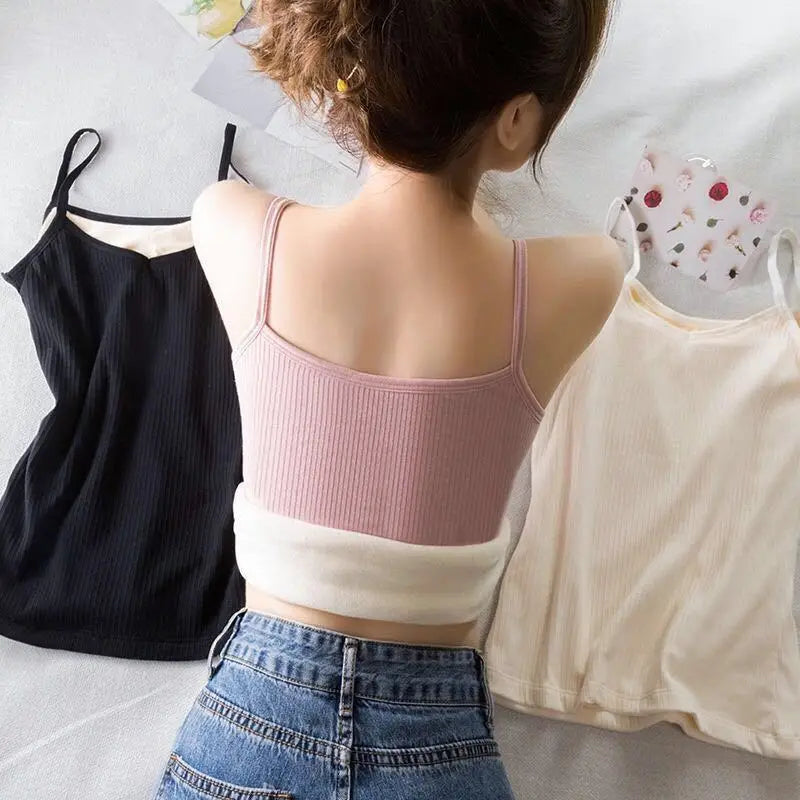 Woman wearing a ribbed, pink camisole crop top with a plush white fleece lining; black and cream options also shown.
