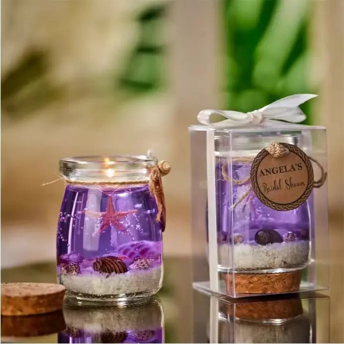 Purple gel candle in a glass jar featuring starfish and seashells, presented in a clear gift box with a ribbon.