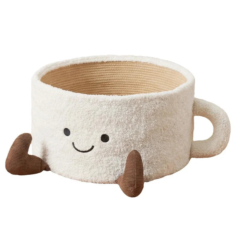 Off-white, mug-shaped cat bed with a smiling face, side handle, brown feet, and internal scratching board.