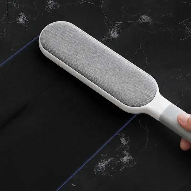 Grey and white lint remover tool being used on black fabric covered in lint.